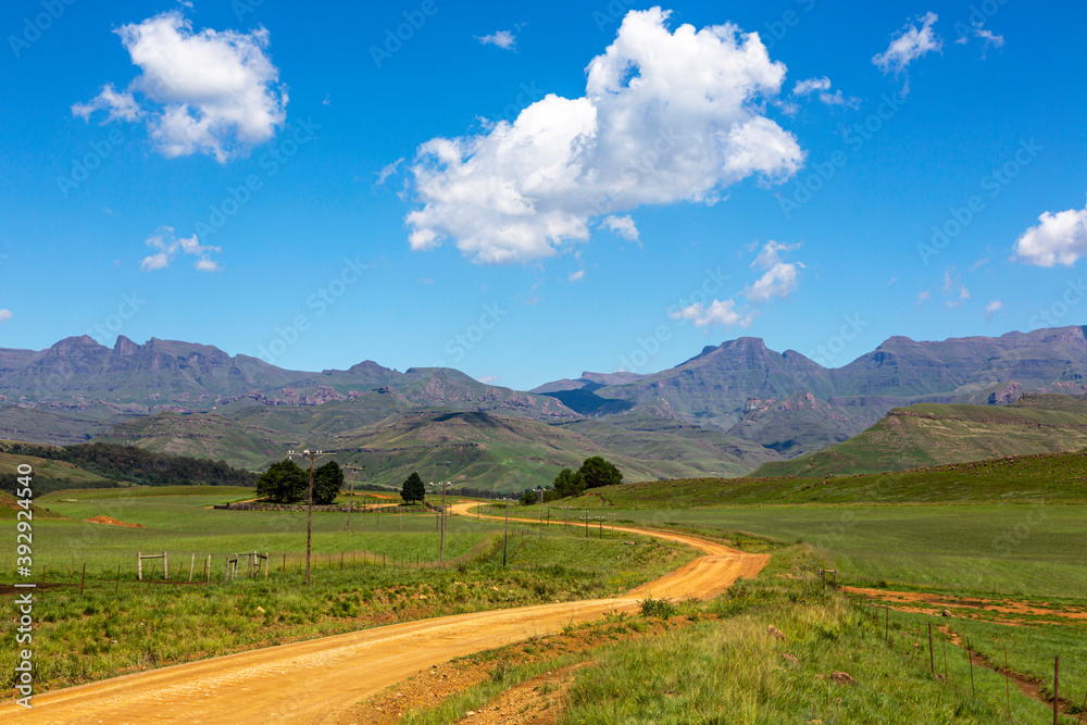 Gravel road through green pastures to the mountain Gravel road through green pastures to the mountain