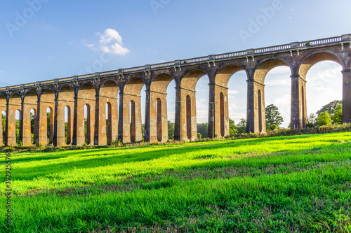 A view of the Ouse Valley Viaduct (Balcombe Viaduct) in the summer with bright sun shining through the arches onto the grass photo