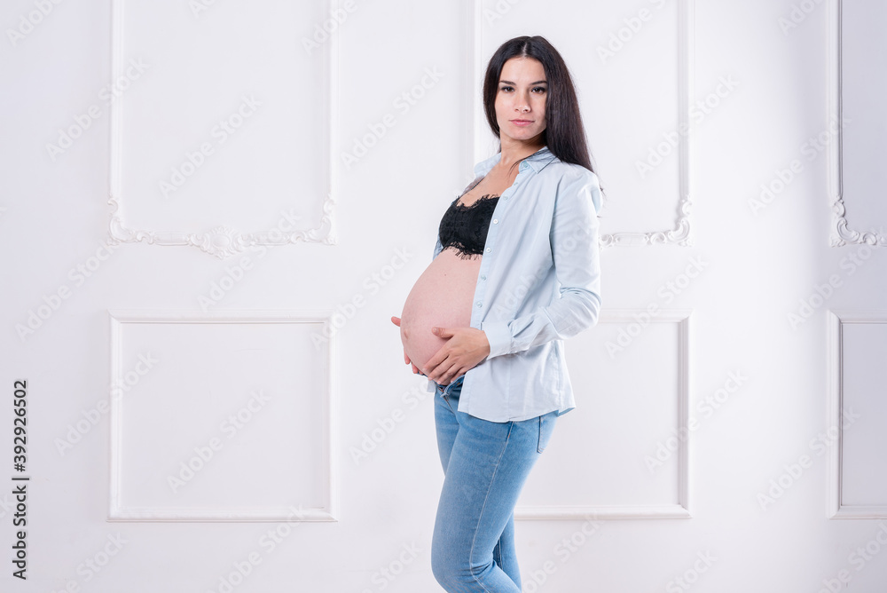 Happy pregnant girl in jeans and unbuttoned shirt