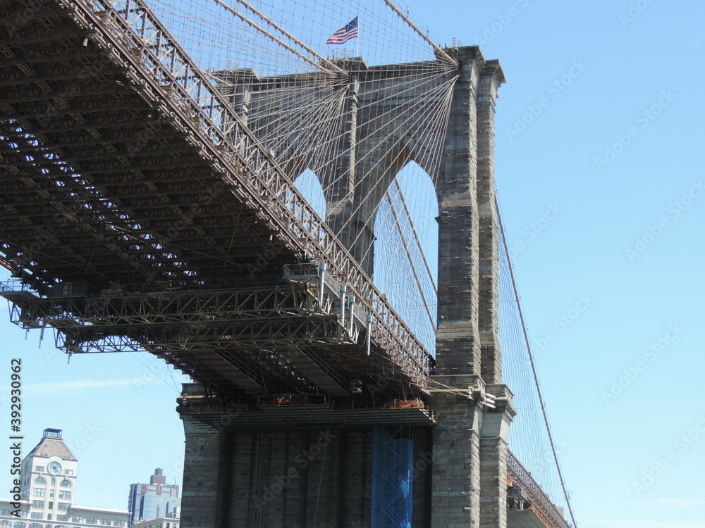 Fototapeta premium El Brooklin Bridge con la Bandera de USA en la torre, que se une con Manhattan (Ney York) visto desde el Crucero de paseo en un dia despejado, 11-05-2014