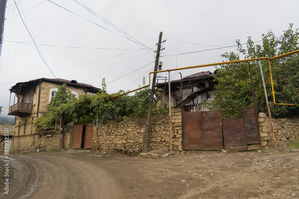 Street with big metal door and balcony house with disorganized electric cables and yellow gas pipes in the city of Hadrut part of the Janapar Trail in Nagorno Karabakh in the Republic of Artsakh Street with big metal door and balcony house with disorganized electric cables and yellow gas pipes in the city of Hadrut part of the Janapar Trail in Nagorno Karabakh in the Republic of Artsakh