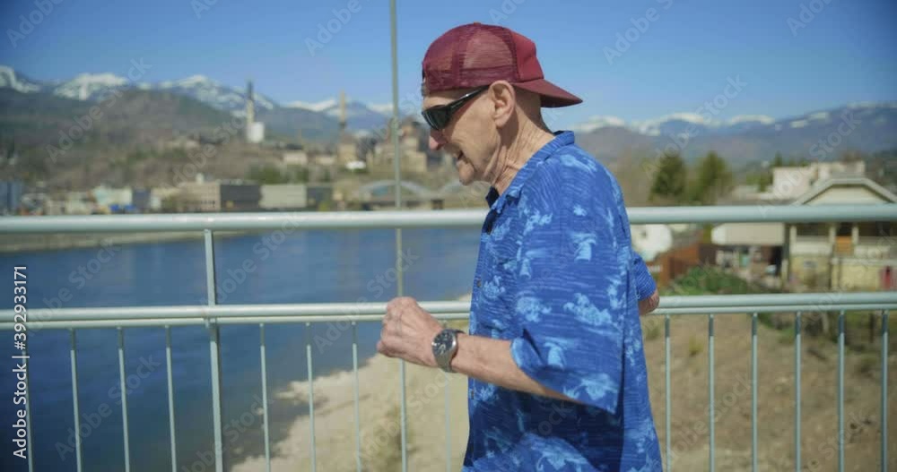 Medium shot, elderly man walks across river bridge Medium shot, elderly man walks across river bridge