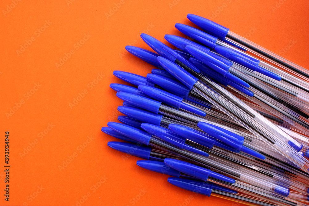 Fototapeta premium Ballpoint pens for writing on brown background. View from above. The case handles white, caps blue. Handles are located in the bottom right corner. Education. Schooling. For work. Flatlay. Copy spase.