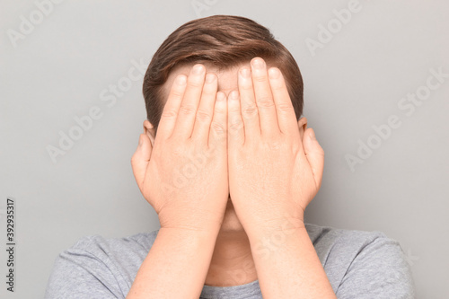 Portrait of blond man covering his face with hands