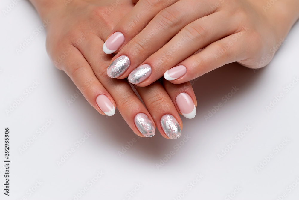 wedding french white manicure with silver decor, matte foil on short oval nails close-up on a white background. wedding french white manicure with silver decor, matte foil on short oval nails close-up on a white background.