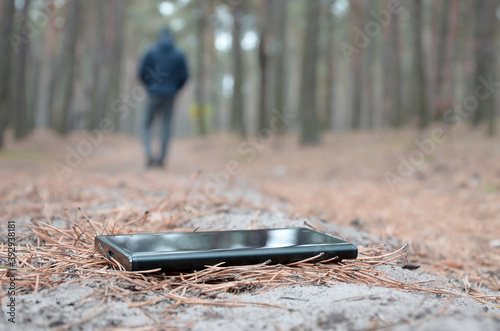 Young man loses his smartphone on Russian autumn fir wood path. Carelessness and losing expensive mobile device concept