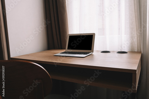 Laptop on work table in empty room or office. Off laptop with blank screen in the interior of the room.