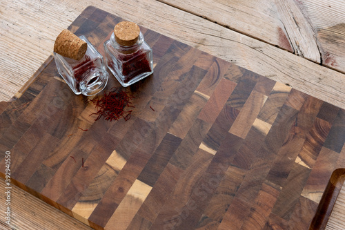 Saffron spice in small glass jars with a beautiful and rustic cutting board, place for recipes.