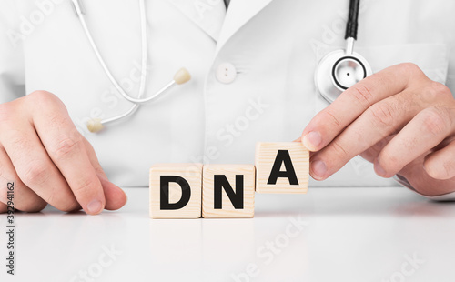 Doctor holds wooden cubes in his hands with text DNA