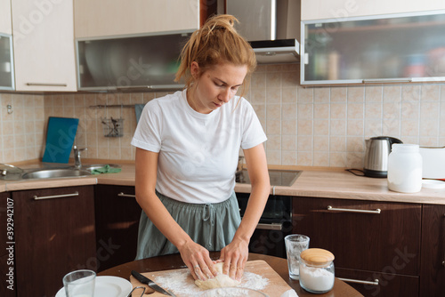 Photography Young girl preparing dough on a kitchen. Home baking