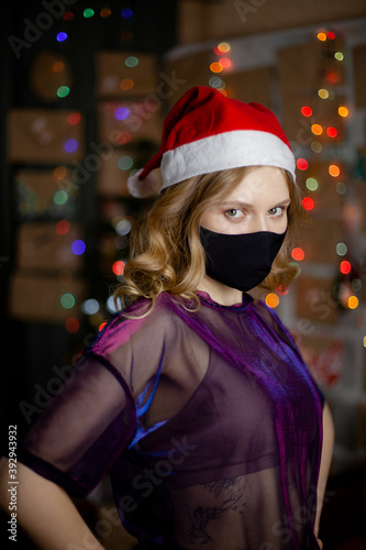 Portrait of a beautiful girl in medical mask, standing in front of decorated christmas tree at home
