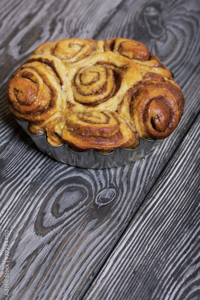 Baked cinnabons in shape. Stand on black composite boards. Close-up shot. Baked cinnabons in shape. Stand on black composite boards. Close-up shot.