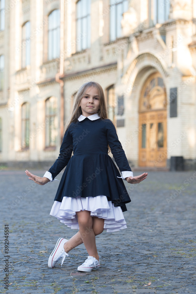 Fototapeta premium Cute little dance girl in school uniform make curtsy outdoors, dancing