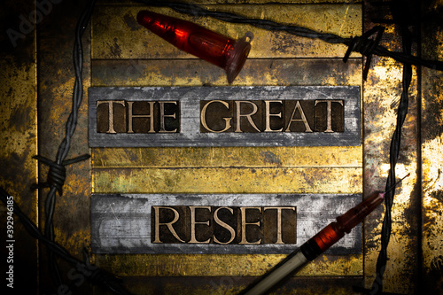 The Great Reset text message on textured grunge copper and vintage gold background with barbed wire and syringe and laboratory vial filled with red fluid
