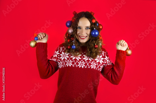 Beautiful girl with christmas toys in hair on red background