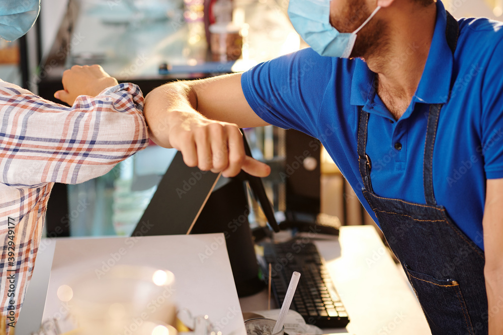 Close-up image of female customer giving elbow bump to coffeeshop barista