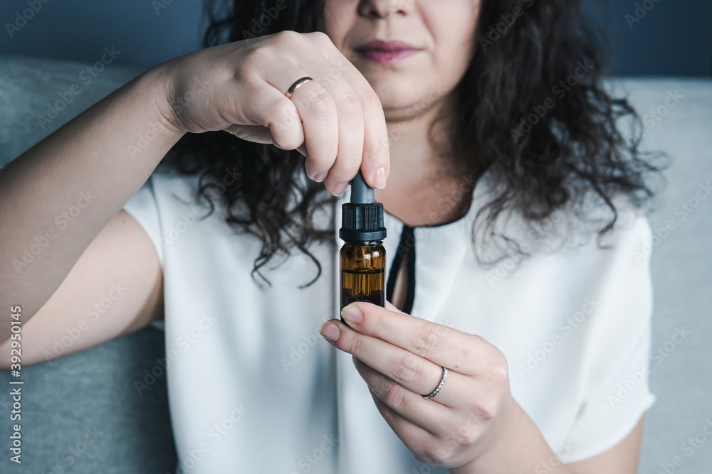 Fototapeta premium Close-up of females hand holding bottle with cbd oil drops