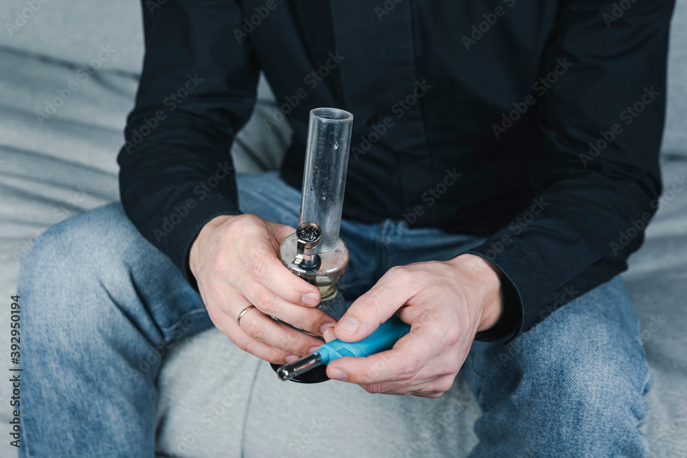 The young person smoking medical marijuana with bong, indoors