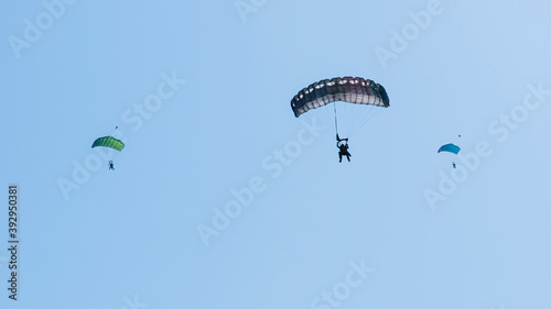 Tandem parachute jump. Silhouette of skydiver flying in blue clear sky