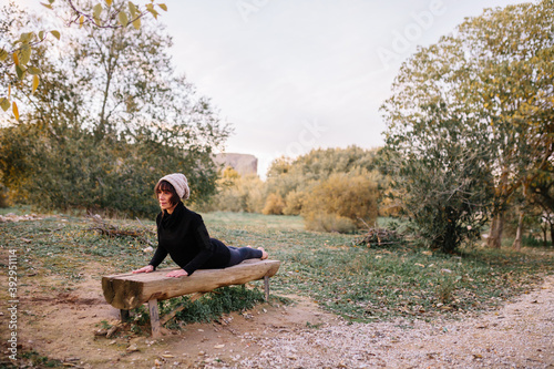 Woman practicing yoga and stretching on the park bench