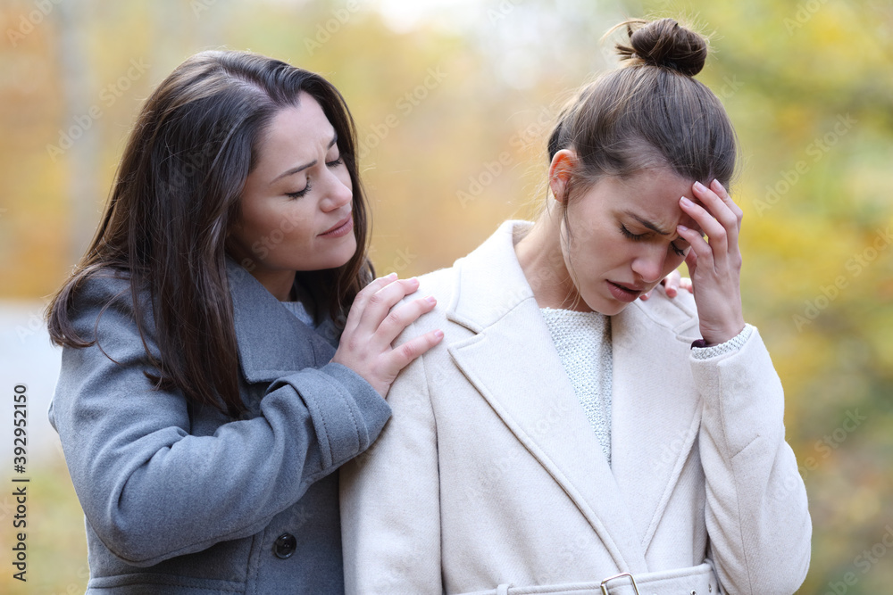 Woman comforting her sad friend in a park in winter Woman comforting her sad friend in a park in winter