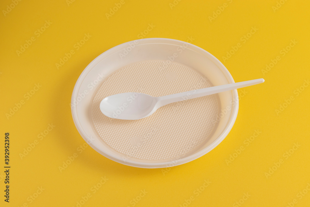 Disposable plastic plate and spoon on a yellow background. Disposable plastic plate and spoon on a yellow background.