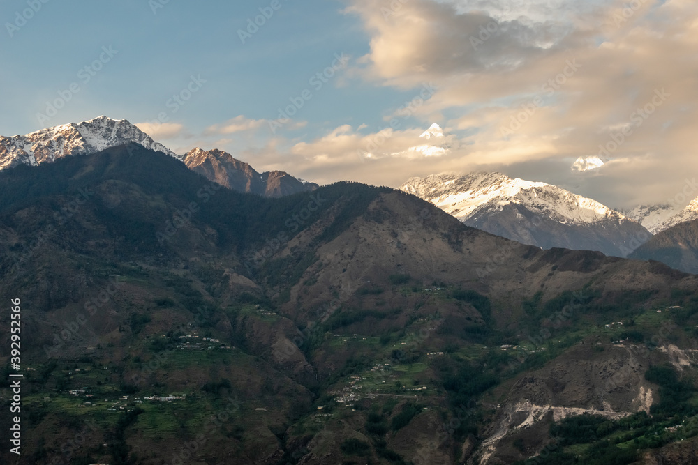 Himalayan mountains of the Panchachuli range towering above a green hillside around the village of Munsyari in Uttarakhand.