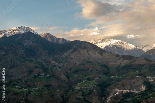 Himalayan mountains of the Panchachuli range towering above a green hillside around the village of Munsyari in Uttarakhand.