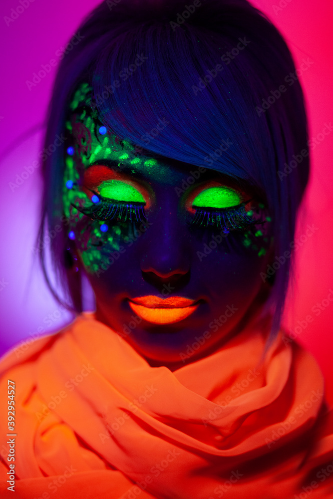 Close-up front portrait of a female model with amazing colorful neon makeup, and orange scarf on neck.