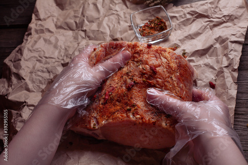 Fotografi hands in transparent plastic gloves rub spices into meat on food craft paper, close-up