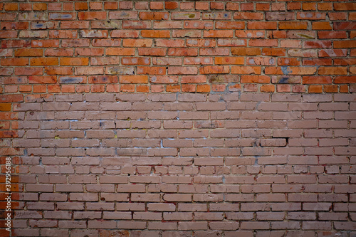 Background. A large wall of red brick half-painted paint.