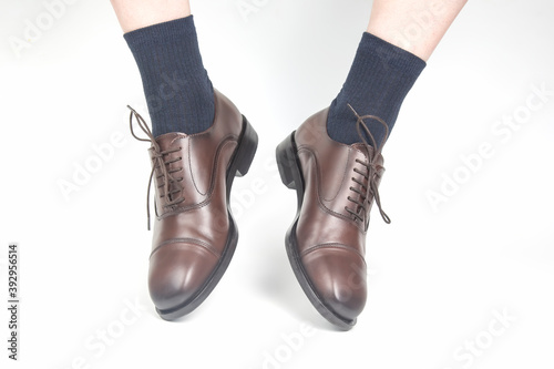 Male legs in socks and brown classic leather shoes on a white background