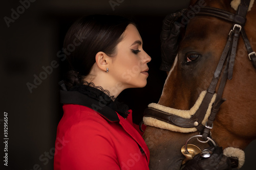 Woman jockey rider hugs brown horse with eyes closed. Concept love animals