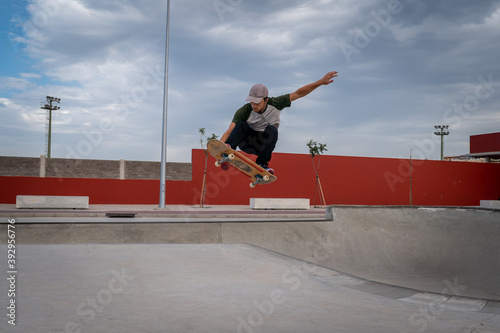 
Hombre joven hace un truco llamado melon grab en un parque de skate photo