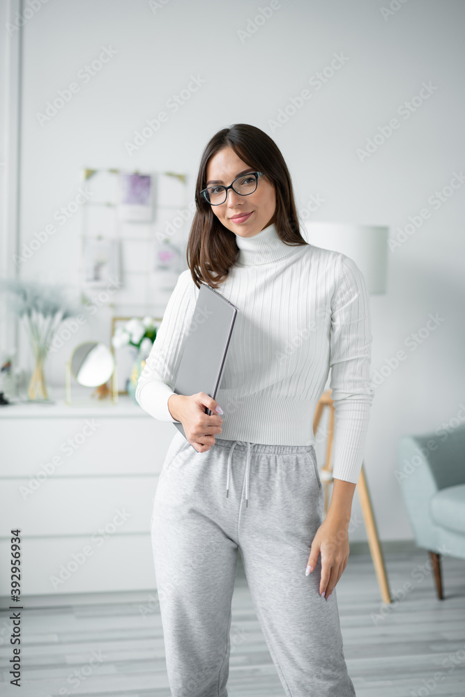 Young woman coach in glasses stands with laptop. Young woman coach in glasses stands with laptop.