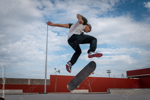 
joven hace un truco llamado heelflip en un parque de patinaje. movimiento 2 photo