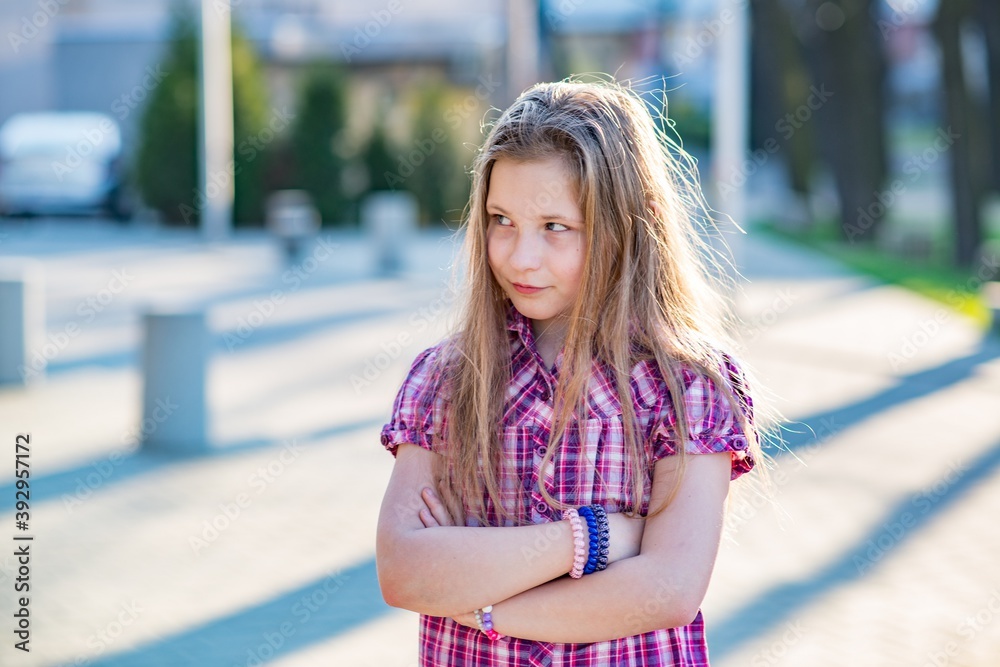 Offended girl 10 years old with long hair and a checked shirt.