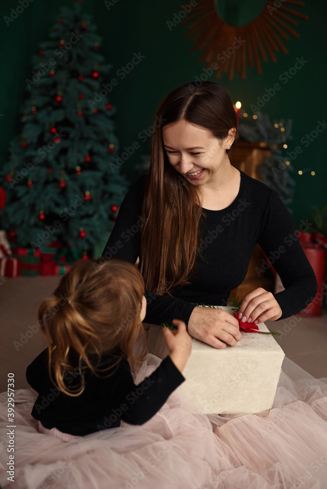 Portrait of a young mother with her little daughter having fun and opening Christmas presents. Portrait of a young mother with her little daughter having fun and opening Christmas presents.