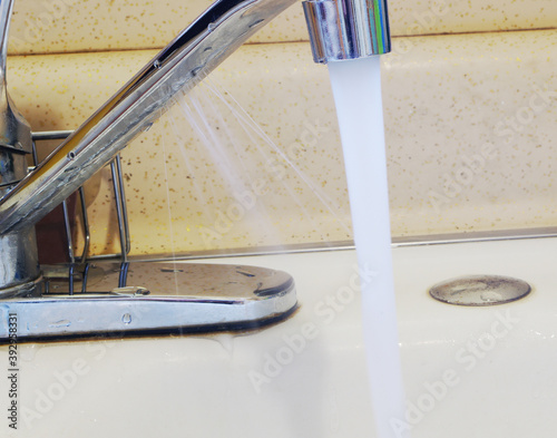 The untamed water spray coming from the corroded chrome kitchen faucet