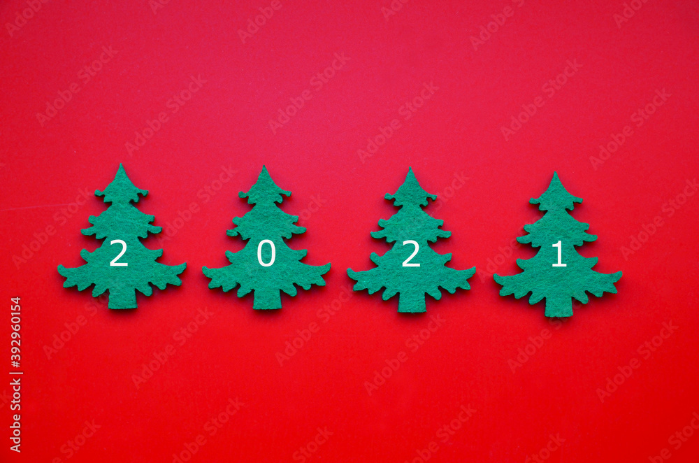 New Year 2021 greeting card with green fir trees on red background. Winter holidays minimal flat lay concept for design.Selective focus.