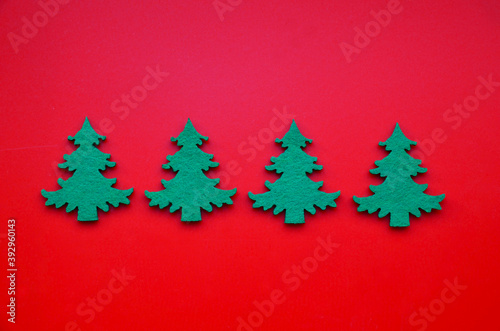 Winter festive decoration with green fir trees on red background. Christmas or New Year minimal flat lay concept for design.Selective focus.
