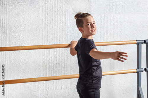 A beautiful young man looks into the camera and learns ballet at a ballet school. The hand on the ballet Barre.