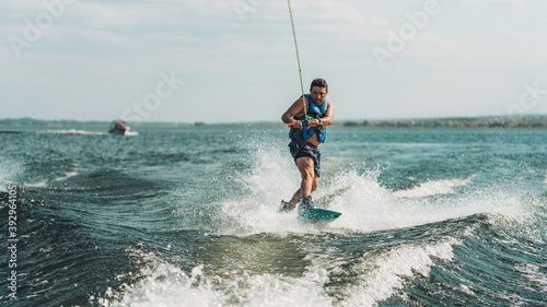young man doing wakeboarding in a lake whit mountains also doing jumps