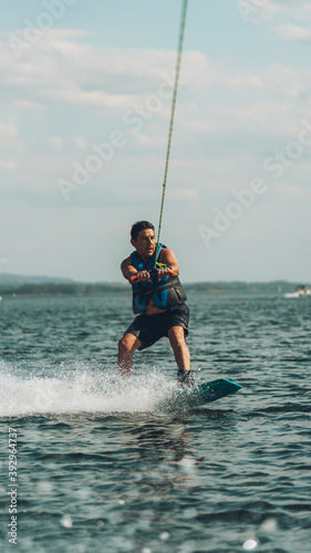 young man doing wakeboarding in a lake whit mountains also doing jumps © Juanmarcos