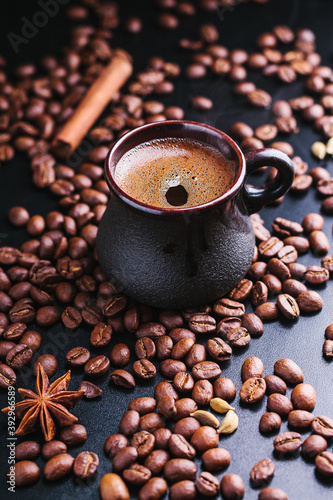 Cup of coffee with a scattering of coffee beans on a dark background