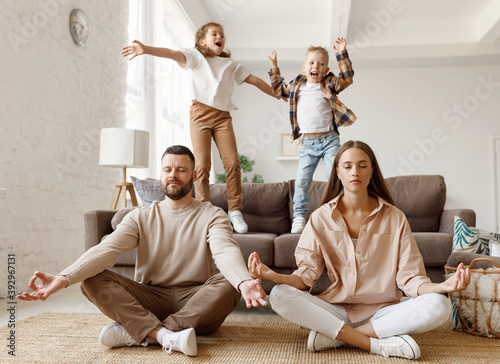 Happy parents  meditating in room with playful kids. photo