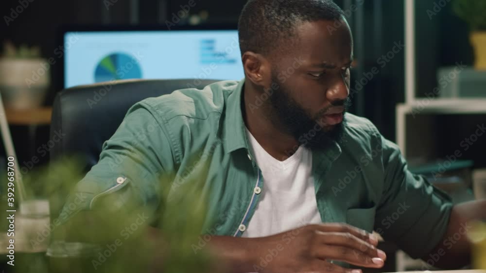 African business man reading document indoors. Annoyed afro man looking diagram African business man reading document indoors. Annoyed afro man looking diagram
