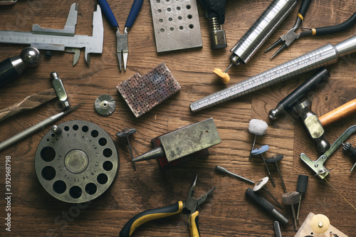 Top view jewelry maker workbench with tools on table. Equipment and tools of a goldsmith on wooden working desk inside a workshop. photo