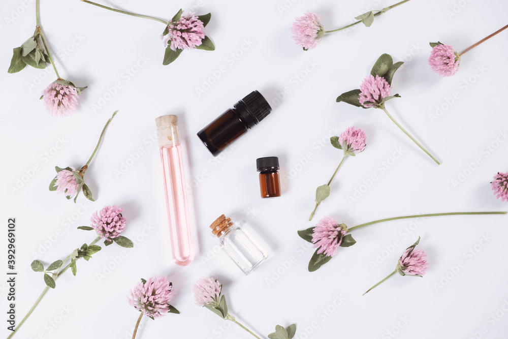 Composition with rose essential oil and flowers on white background, top view Composition with rose essential oil and flowers on white background, top view