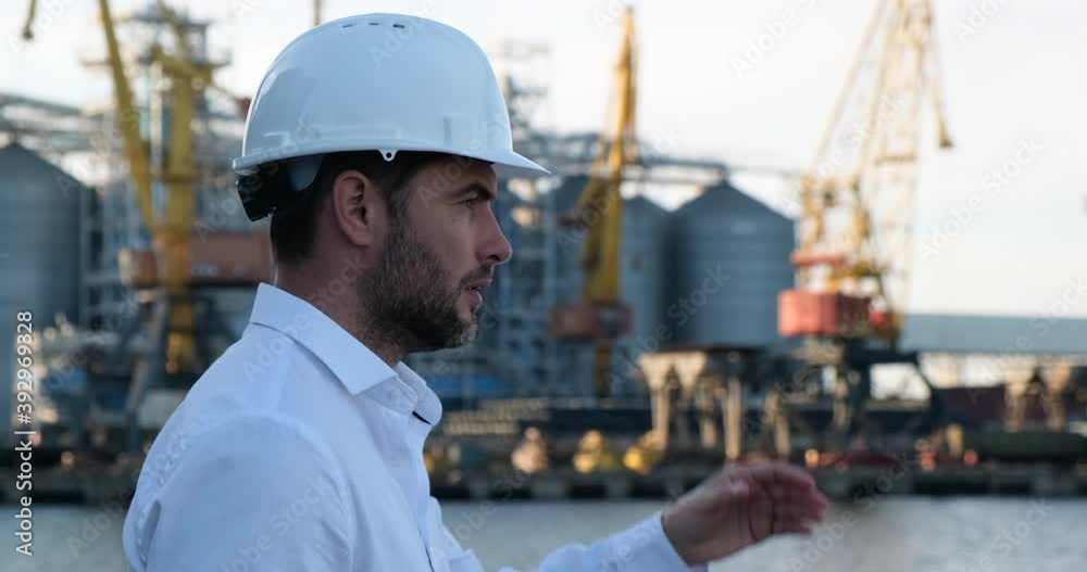 Young serious man in helmet drinking coffee in a sea port Young serious man in helmet drinking coffee in a sea port